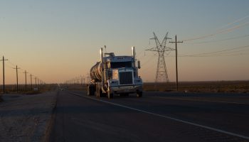 A truck drives down a West Texas road during sunset.