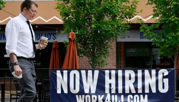 A man walks past a "now hiring" sign posted outside of a restaurant in Arlington, Virginia on June 3, 2022.