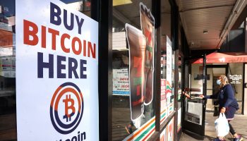 A "Buy Bitcoin Here" sign is posted at a 7-Eleven store in 2021 in Los Angeles.