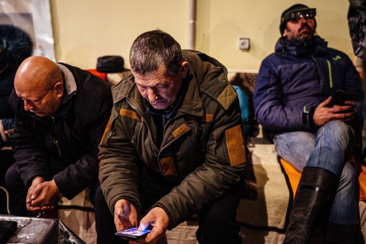 A Ukrainian resident looks at his mobile phone as he and others rest in a humanitarian aid centre in Bakhmut, Donetsk region