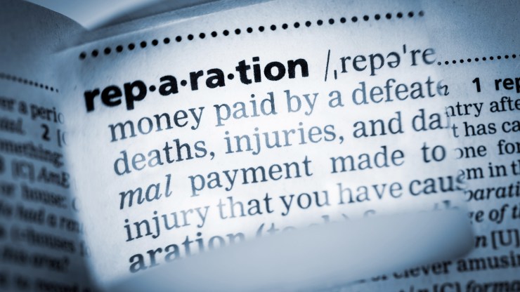 The dictionary definition of the word “reparation” photo taken through a magnifying glass.