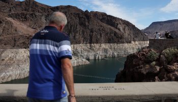 Park visitors look at a bleached 'bathtub ring' that is visible on the banks of Lake Mead near the Hoover Dam on August 19, 2022 in Lake Mead National Recreation Area, Arizona