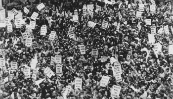 A black and white photo shows hundreds of protestors holing signs reading "Union Justice Now!" and "Honor King: End Racism!" in Memphis in April 1986, several days after the assassination of Dr. Martin Luther King Jr.