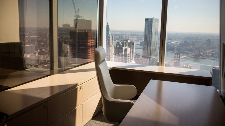 An office with a chair and desk overlooks New York City.