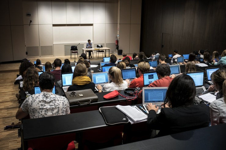 Students in a lecture hall look at their laptops.
