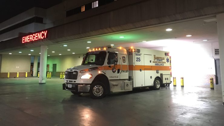An ambulance sits outside a hospital emergency room at night.