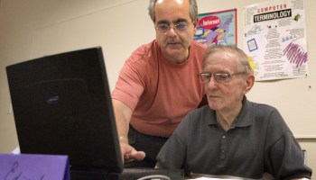 Instructor Lee Huber (L) helps 83-year-old Edward Jelen as he works on his laptop computer during an "Introduction to Microsoft Word" computer class in Des Plaines, Illinois.