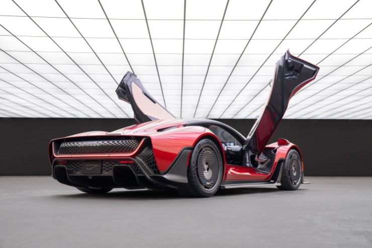 A red Czinger 21C — a futuristic-looking sports car whose doors open up — sits right in the middle of a large, empty room whose ceiling is entirely composed of rectangular panels of light.