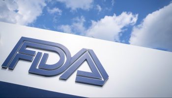 The FDA (Food and Drug Administration) logo is posted on a sign and set against a partly cloudy sky.