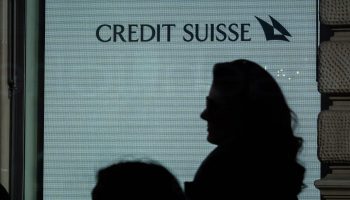 The logo for Credit Suisse behind the silhouette of a woman.