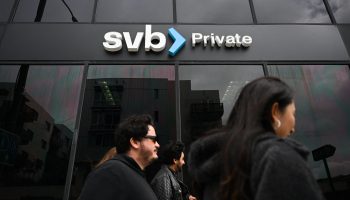 People walk past dark-tinted windows with a sign above reading SVB Private.