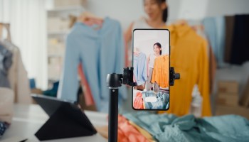 A woman is seen in this photo live-streaming to sell clothes from home.
