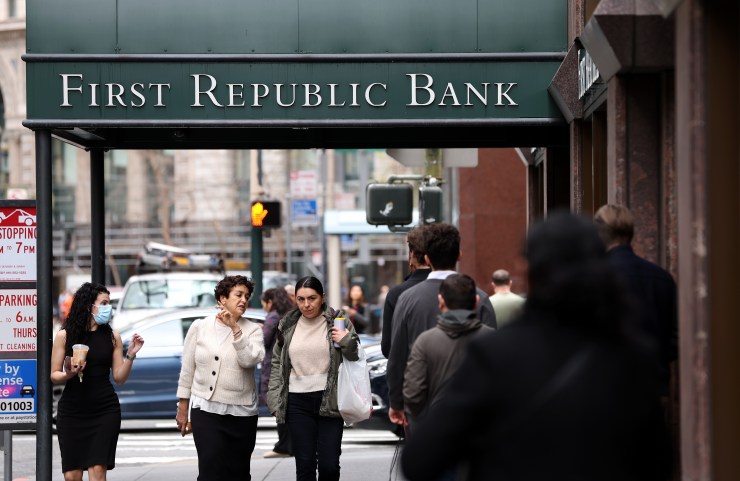 People on a busy San Francisco street walk under a green awning with First Republic Bank written on it.