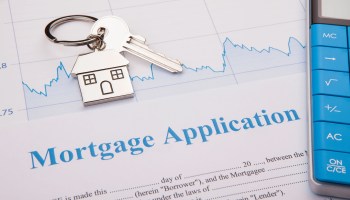 A mortgage application sits on a desk, with a property key and a calculator.