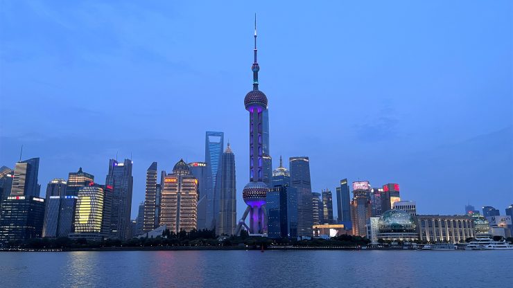 The Shanghai skyline is reflected on the water at dusk.