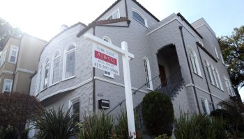 A for sale sign is posted in front of a large, gray home on Feb. 20 in San Francisco.
