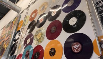 Multi-colored vinyl records are displayed on a white wall inside the Burlington Record Plant.