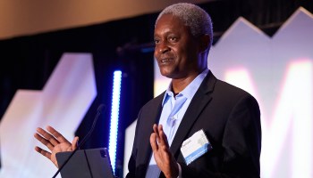 Raphael Bostic, president and CEO of the Federal Reserve Bank of Atlanta, speaks at a conference wearing a black suit and blue button-up shirt.