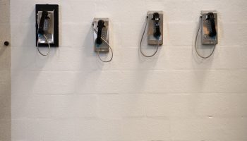 Four phones mounted on a white cement block wall.