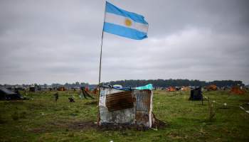 An Argentine flag flutters amid makeshift iron shelters on land occupied by homeless people.