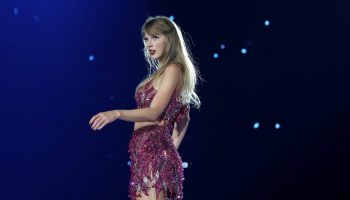 Taylor Swift performs on stage in a shimmery, purple outfit