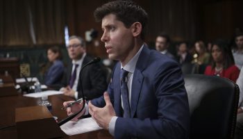 Samuel Altman, CEO of OpenAI, wearing a navy suit sits and testifies (with a blur of people behind him) before the Senate Judiciary Subcommittee on Privacy, Technology, and the Law in Washington, DC.