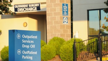 A sign in front of a hospital points visitors to outpatient services and parking.