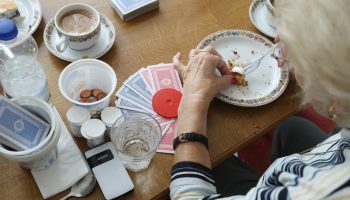An elderly women finishes eating a piece of cake while taking a break during a card game. Around 10 percent of Americans over 50 live alone without significant others or children to care for them, according to AARP.