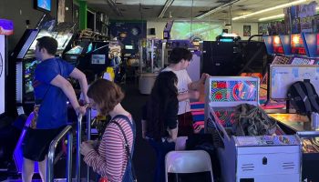 A busy arcade with customers playing ski ball and rhythm games.