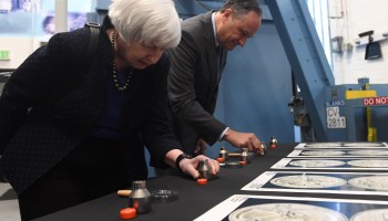 Treasury Secretary Janet Yellen leans over a table, inspecting dies used at the Denver mint.