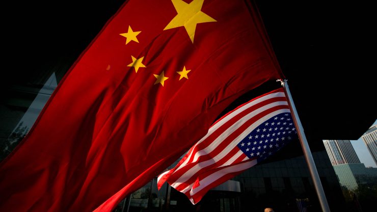 A Chinese and American flag wave in the wind next to one another.