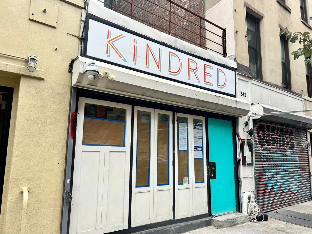 A small restaurants has a sign reading "Kindred" and features a teal door. 