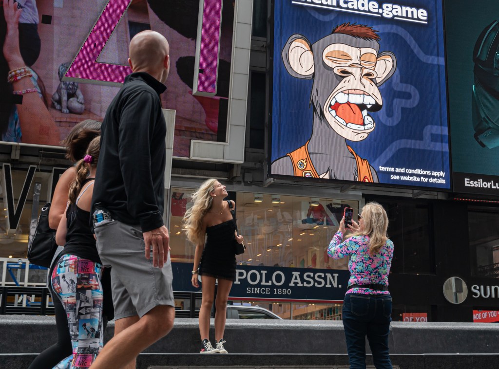 People take photos by a Bored Ape Yacht Club NFT billboard in Times Square in June 2022. 